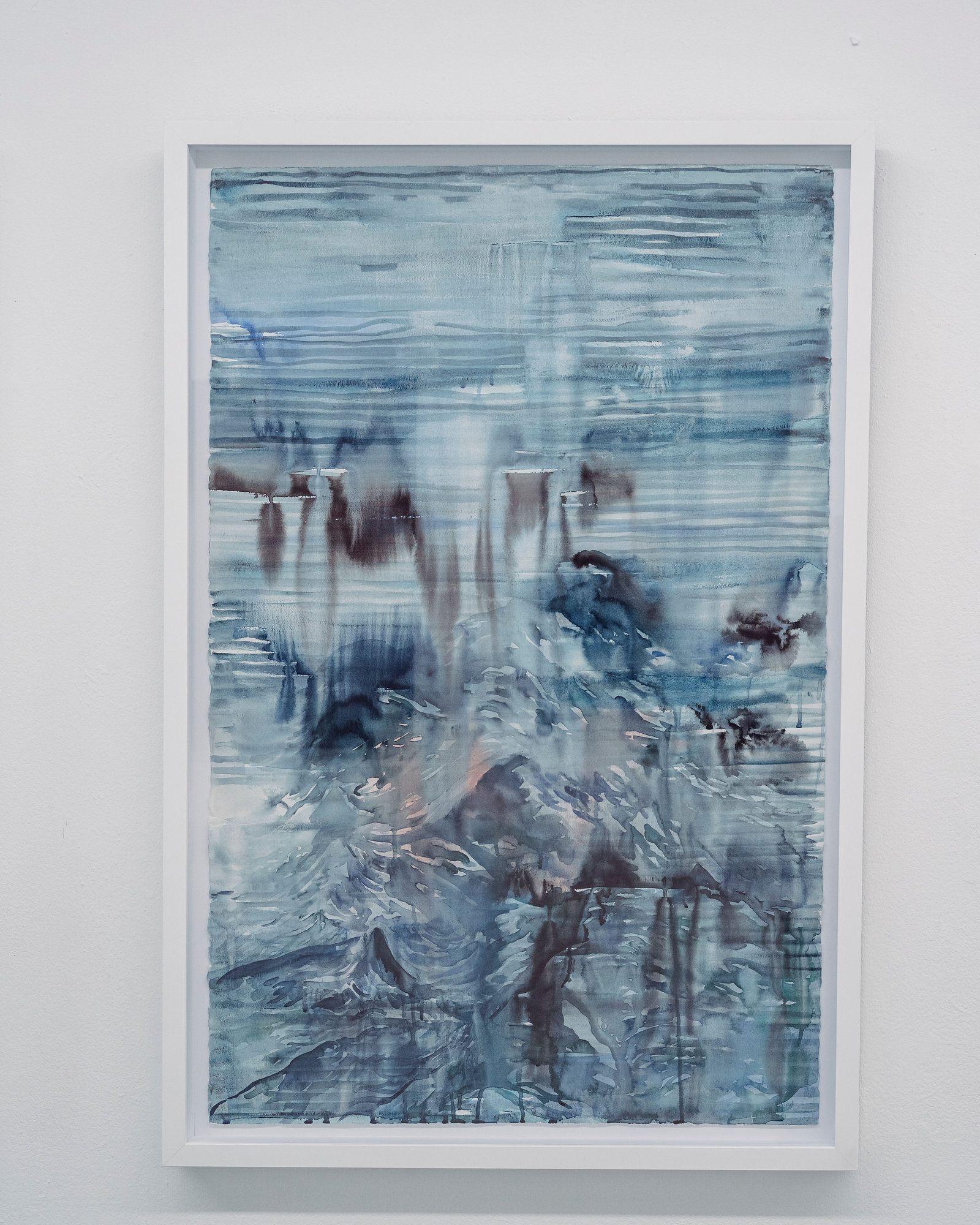 A framed blue and white abstract painting hanging alone on a softly lit white wall