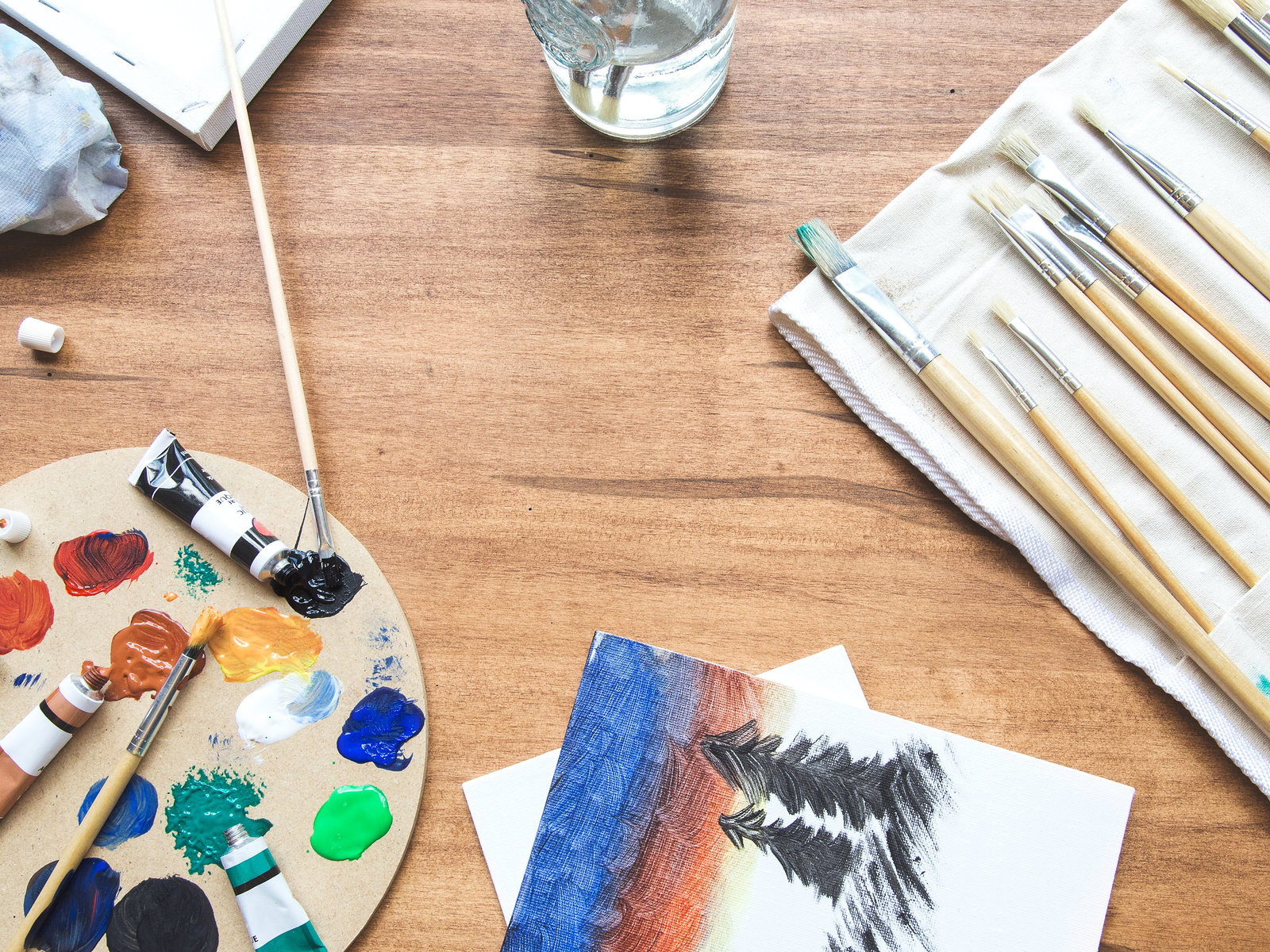 A sunny worktable with a paint palette, brushes and a small study
